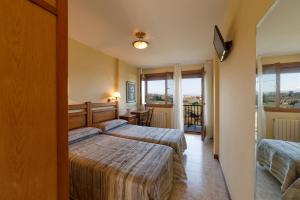 a hotel room with two beds and a balcony at El Mirador de Trasvia Comillas in Trasvia