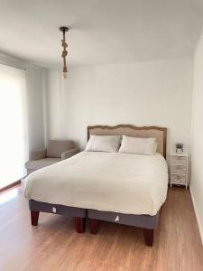 1 dormitorio con 1 cama grande con colcha blanca en Acogedora casa al borde del Río Pingueral, en Dichato