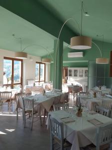 un restaurante con mesas y sillas blancas y paredes verdes en Agriturismo Nonno Ninuccio, en Gioi