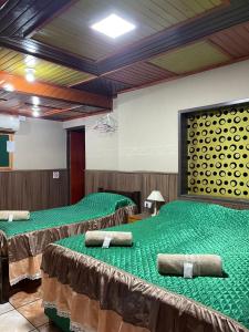 a room with three beds with green sheets at Residencial Arcoiris in Puerto Iguazú