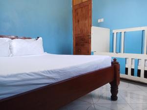 a bed in a room with a blue wall at Magical Fharhana House in Malindi