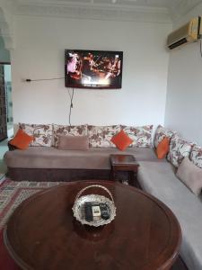 Marrakech في مراكش: غرفة معيشة مع أريكة وتلفزيون على الحائط
