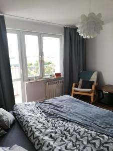 a bedroom with a bed and a chair and windows at Apartament w centrum in Włodawa