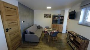 uma pequena sala de estar com uma mesa e um sofá em Przystanek Tykocin - apartamenty gościnne em Tykocin