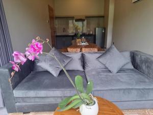 a gray couch with pillows and flowers on a table at MAYURA BALI VILLA in Munduk