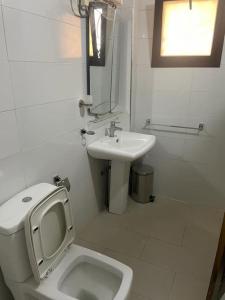 a white bathroom with a toilet and a sink at Appartement à Résidence Mamouja in Dakar