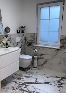 a marble bathroom with a toilet and a window at Gemütliche Wohnung im Herzen von Schwäbisch Gmünd in Schwäbisch Gmünd