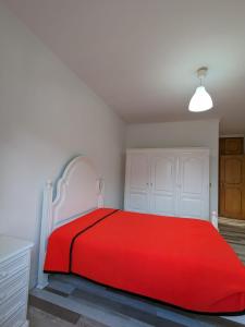 Santi Guesthouse : سرير احمر في غرفة بيضاء مع بطانيه حمراء