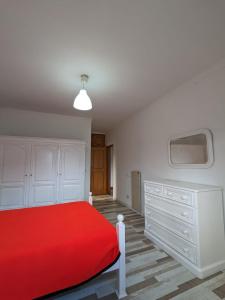 ein weißes Schlafzimmer mit einem roten Bett und einem TV in der Unterkunft Santi Guesthouse 