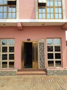 um edifício cor-de-rosa com uma porta amarela e janelas em MARVELLOUS hotel em Lagos