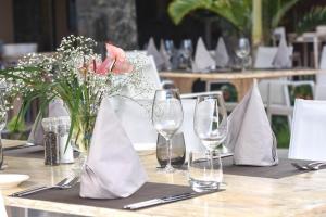 a table with wine glasses and a vase of flowers at Hacienda Plaza Boutique Hotel in Pereybere