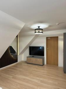 a living room with a flat screen tv and a staircase at Motel Za Miedzą in Bralin