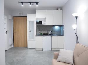 a kitchen with white cabinets and a couch in a room at SunApart A182 in Warsaw
