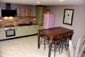 une cuisine avec une table en bois et un réfrigérateur rose dans l'établissement Chez Montgaud, à Verdun-sur-Meuse