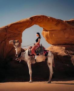 a woman riding on a camel in the desert at Desert Life Camp in Wadi Rum