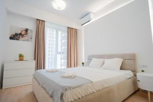 - une chambre blanche avec un grand lit et une fenêtre dans l'établissement X Metropolitan Retreats 2BR in Politehnica Park, à Bucarest