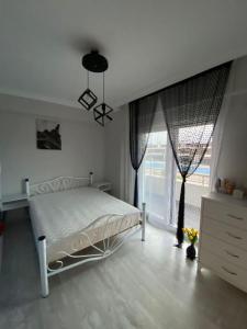 1 dormitorio con cama blanca y ventana grande en Zirve Emlak, en Dikili