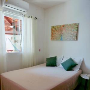 a bed in a room with a window and a painting at Casa com Piscina perto da praia in Salvador
