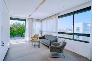 sala de estar con sofá, sillas y ventanas en Shenkin Dream - 4 BR en Tel Aviv