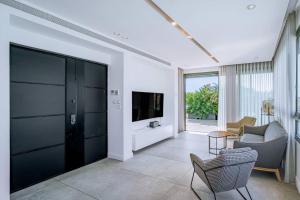a living room with a tv and a couch and chairs at Shenkin Dream - 4 BR in Tel Aviv