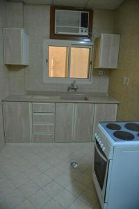 a kitchen with a stove and a microwave at العلمين للشقق المخدومة in Al Jubail