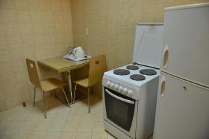 a kitchen with a stove and a table and a refrigerator at العلمين للشقق المخدومة in Al Jubail