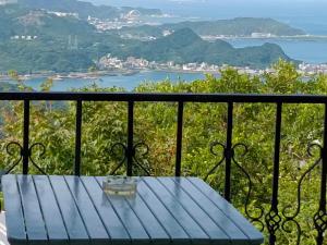 a blue table on a balcony with a view of the ocean at Flower House B&B in Jiufen