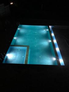 an empty swimming pool with blue water and lights at Swarga Homestay in Mangalore
