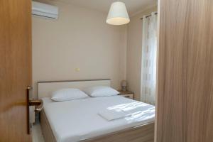 a bedroom with a bed with white sheets and a lamp at Holiday house "Dolka" in Postira