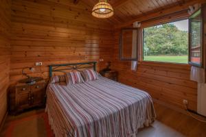 sypialnia z łóżkiem i oknem w drewnianym domku w obiekcie Apartamentos El Cueto w mieście Oviñana