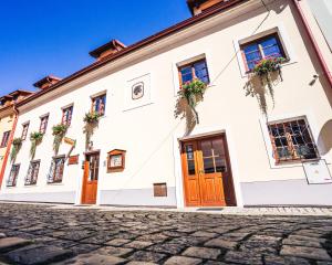 a white building with wooden doors and flowers at Pension Krumau in Český Krumlov