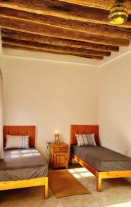 a room with two beds and a wooden ceiling at Maison d'hôtes "Dar Khalifa" in Tozeur