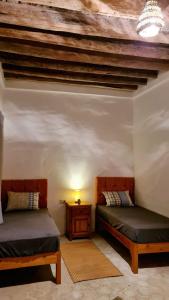 a room with two beds and a table and a ceiling at Maison d'hôtes "Dar Khalifa" in Tozeur