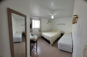 Pokój hotelowy z 2 łóżkami i lustrem w obiekcie Pousada Luar w mieście Santa Cruz Cabrália