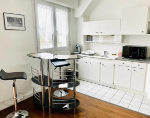 Charmant appartement en bord de Cher في سانت-آفيرتين: مطبخ فيه دواليب بيضاء وطاولة فيه