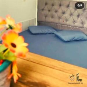 Schlafzimmer mit einem Bett mit blauer Bettwäsche und blauen Kissen in der Unterkunft Pousada Pé na Praia in Imbé