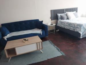 a living room with a blue couch and a bed at Comfy spacious apartment in Pretoria