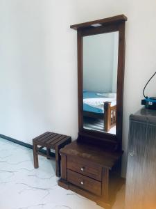 a mirror on a wooden dresser next to a bed at Center Point Villa Unawatuna in Unawatuna
