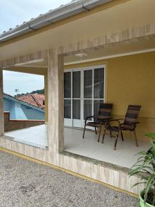 eine Terrasse mit 2 Stühlen und einem Tisch auf einem Haus in der Unterkunft Residência Vó Nilton in Governador Celso Ramos