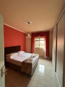 1 dormitorio con cama y pared roja en Acomodação vó Nilton, en Governador Celso Ramos