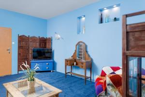 a living room with blue walls and a tv and a table at Stare Miasto Krupnicza in Wrocław