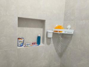 a bathroom with a shelf with toiletries on the wall at Justin Guest House in Jimbaran