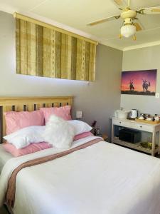 a bedroom with a bed with pink and white pillows at The M-Pire Cottage in Bloemfontein