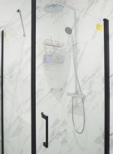 um chuveiro com uma porta de vidro e um chuveiro em MoonApart A2 em Varsóvia