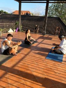 a group of people sitting on mats on a deck at Bali Telaga Hati Yoga Healty And Retreat Center in Sanur