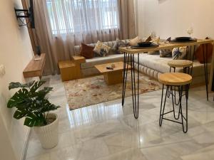 uma sala de estar com um sofá, uma mesa e bancos em Élégance en 40 mètres Nouaceur em Nouaceur