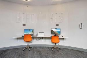 un bureau avec deux bureaux et deux chaises oranges dans l'établissement 17th Floor 1 BR Resort Condo Direct Oceanfront Wyndham Ocean Walk Resort Daytona Beach 1706, à Daytona Beach