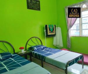 a green room with two beds and a window at ASTANA SHAFIIS in Malacca