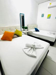 Dos camas en una habitación de hotel con toallas. en Riviera Central Hotel en Montería