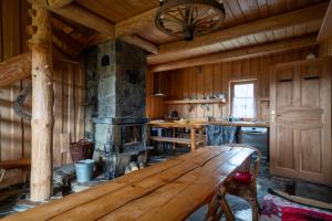 a kitchen with a wooden table and a fireplace at Miętowa Osada Czerwienne in Ciche